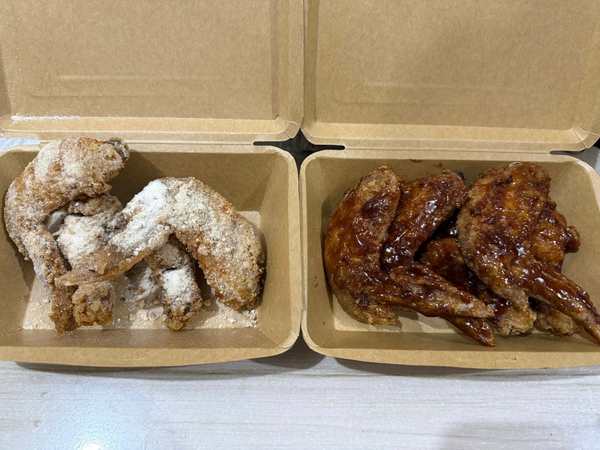 Takam PH sauced and powdered wings in two takeout boxes.